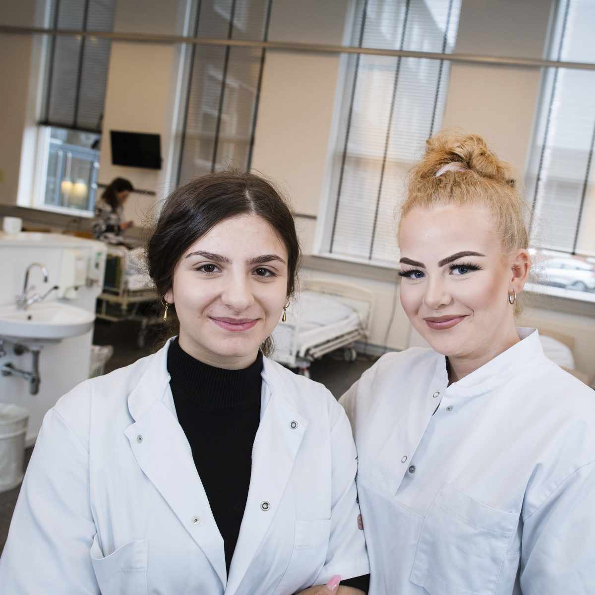 To SOSU studerende poserer foran en sygeseng