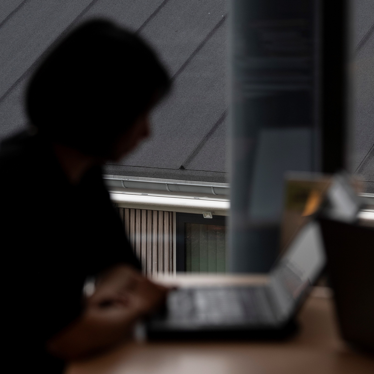 Pige i siluet sidder og arbejder på sin computer